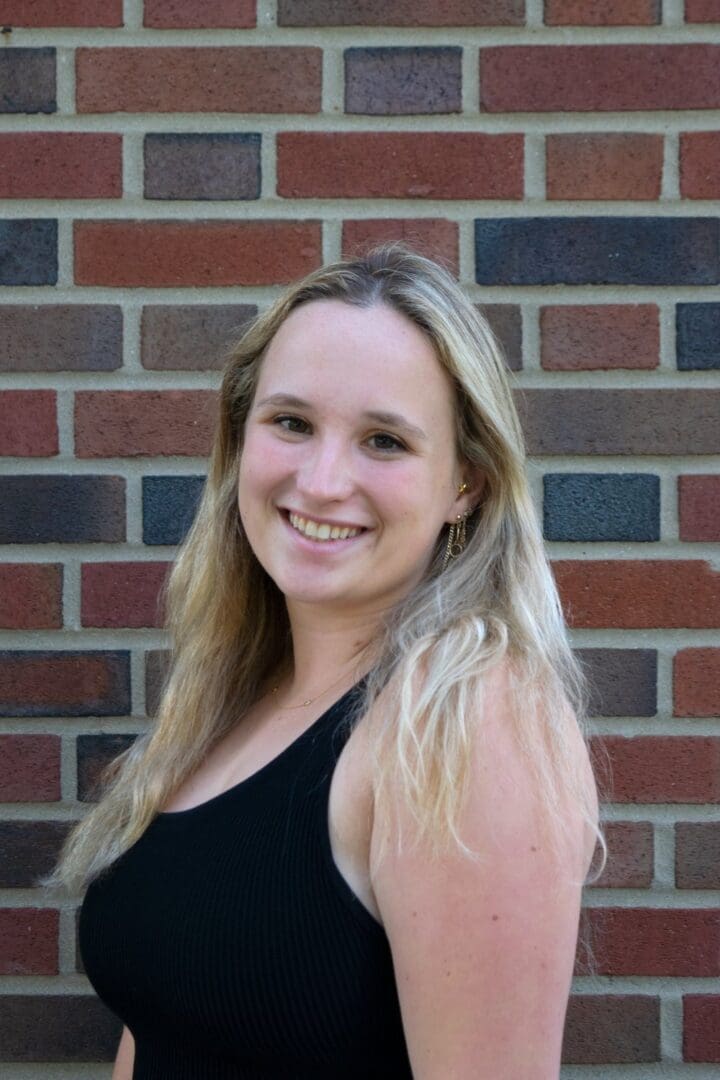 Smiling woman with blonde hair in black tank top.