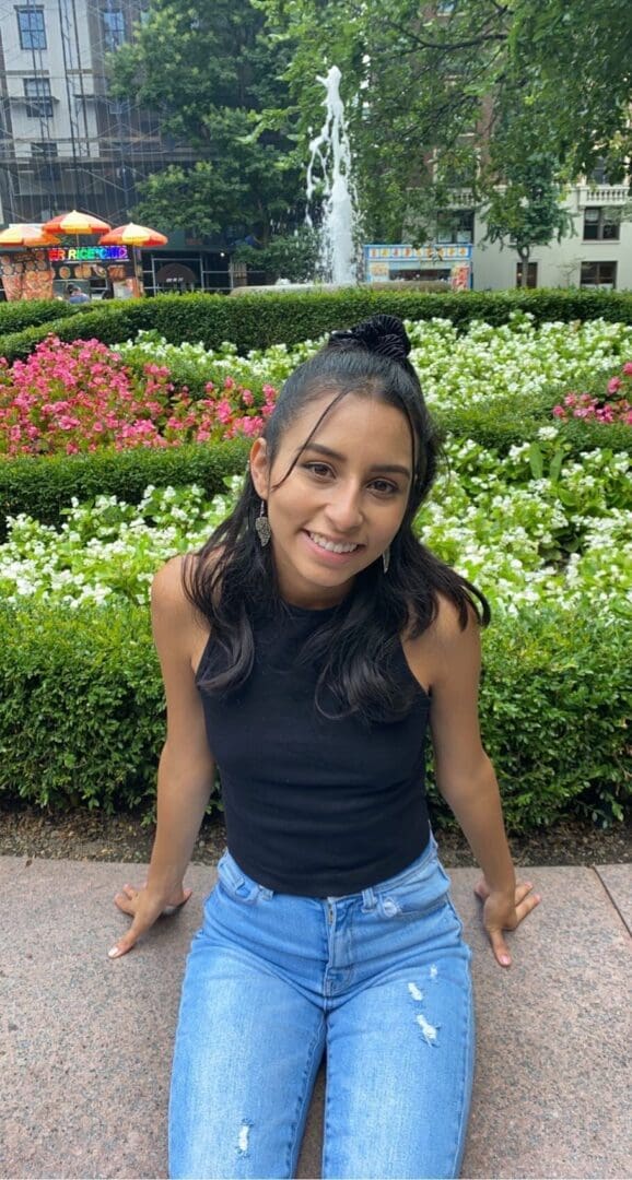 Woman in black tank top and jeans smiling.