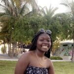 Woman with braids smiling in a park.