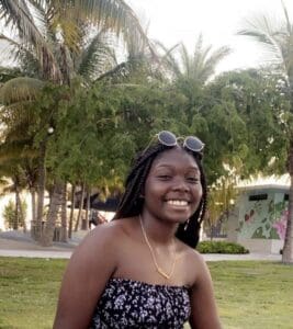 Woman with braids smiling in a park.