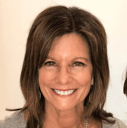 Smiling woman with brown hair and earrings.