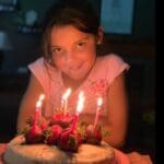 Girl blowing out candles on birthday cake.