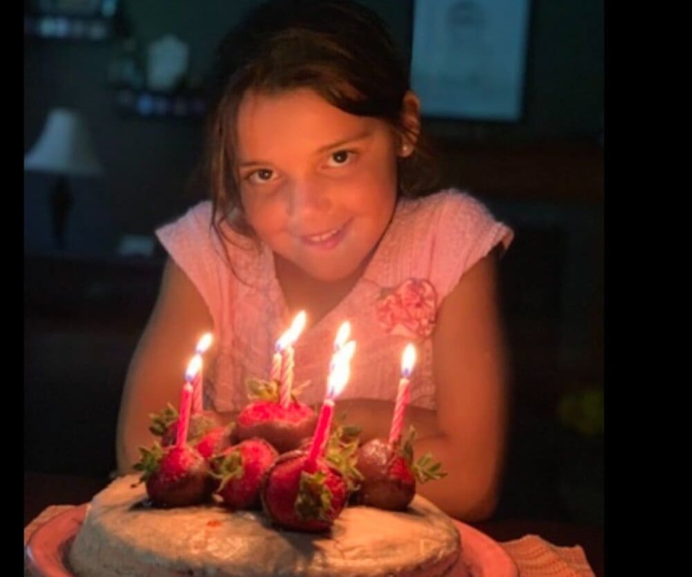 Girl blowing out candles on birthday cake.