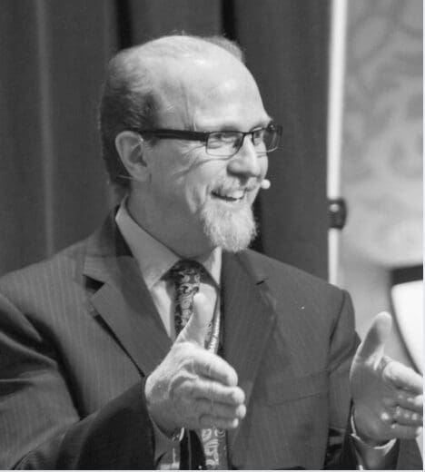 Smiling man in suit giving thumbs up.