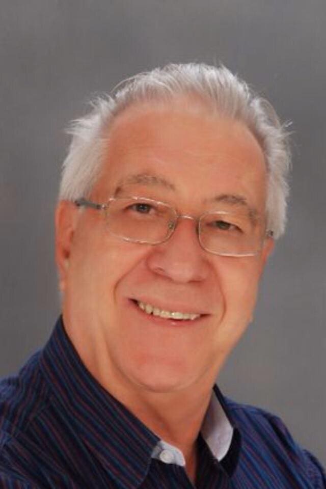 Smiling man wearing glasses and blue shirt.