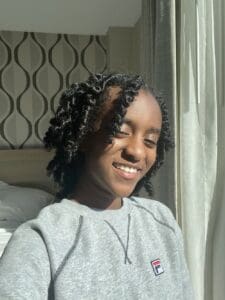 Smiling woman with curly hair wearing a grey sweatshirt.