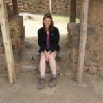 Woman sitting on stone steps in ruins.