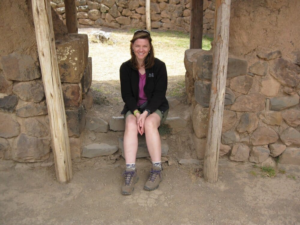 Woman sitting on stone steps in ruins.