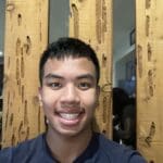 Man smiling in front of wood wall.