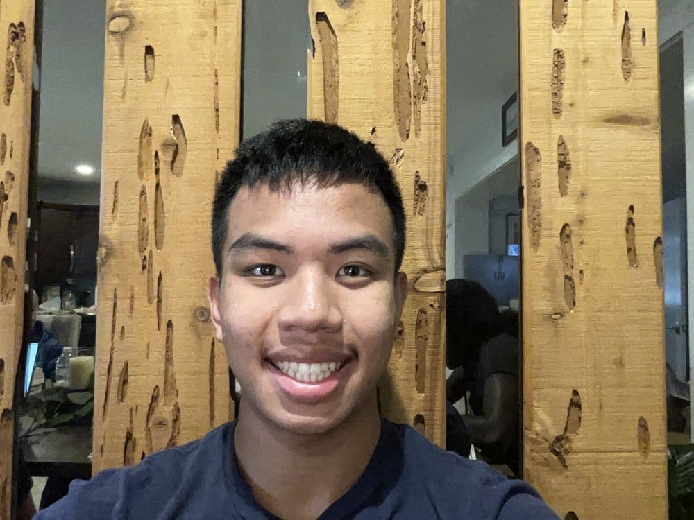 Man smiling in front of wood wall.