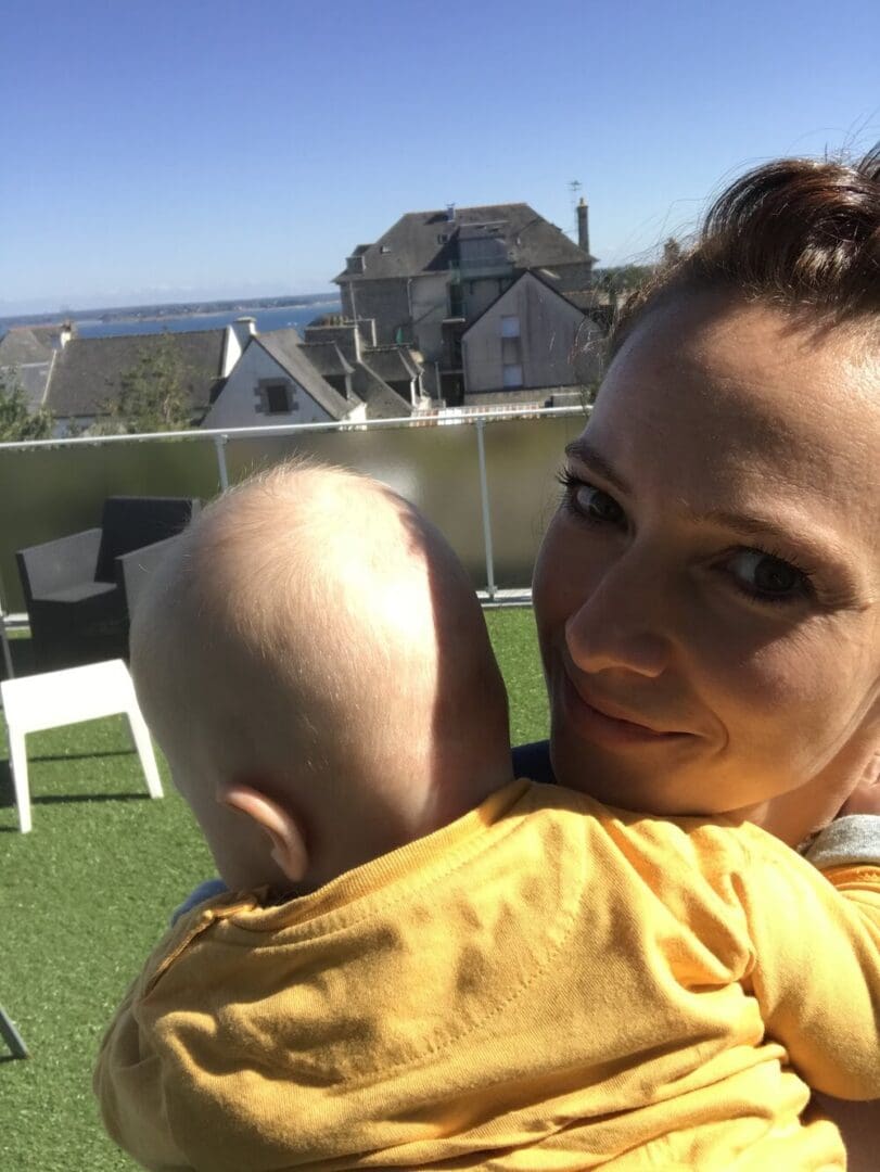 A woman holding a baby on a balcony.