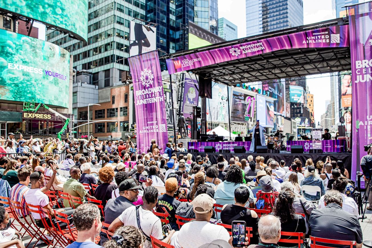 A diverse crowd seated on chairs, attentively facing a stage during an event or performance.