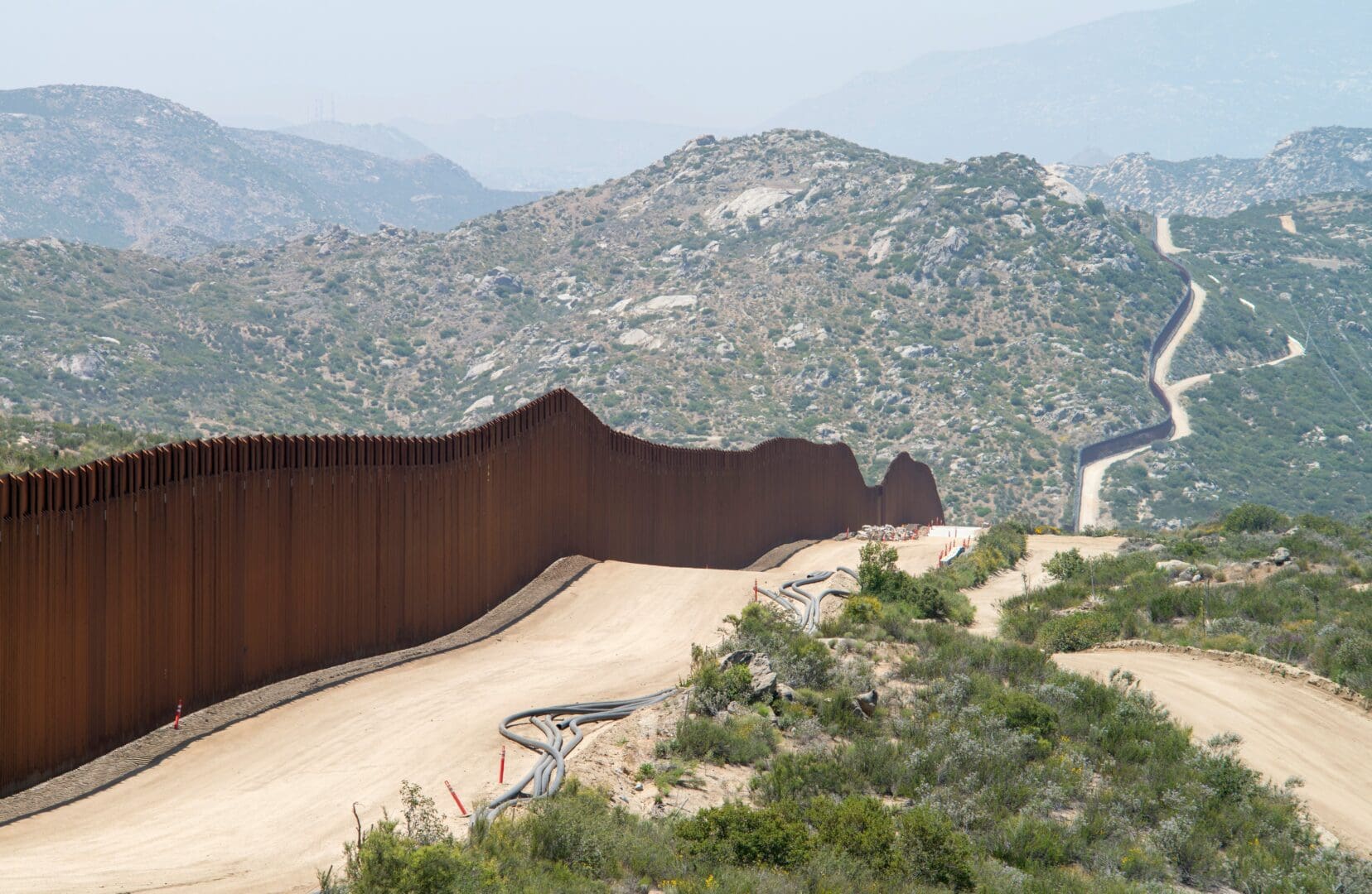 A large border fence stretches across the landscape, symbolizing security and separation between two areas.