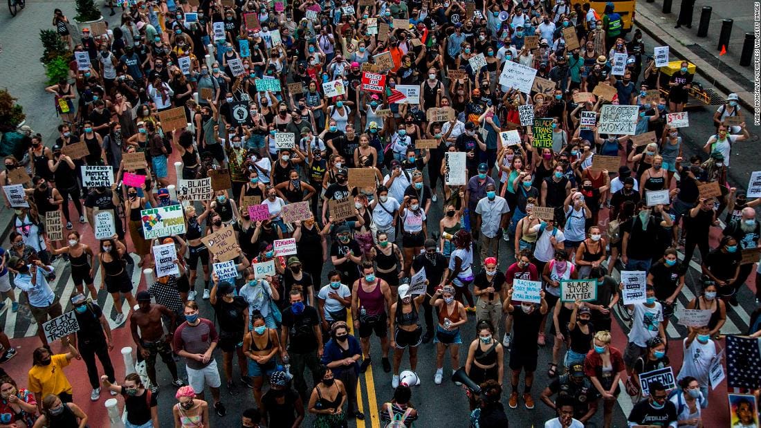 A significant gathering of protesters, each holding signs, collectively voicing their demands for change and equality.