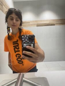 A woman taking a photo wearing orange