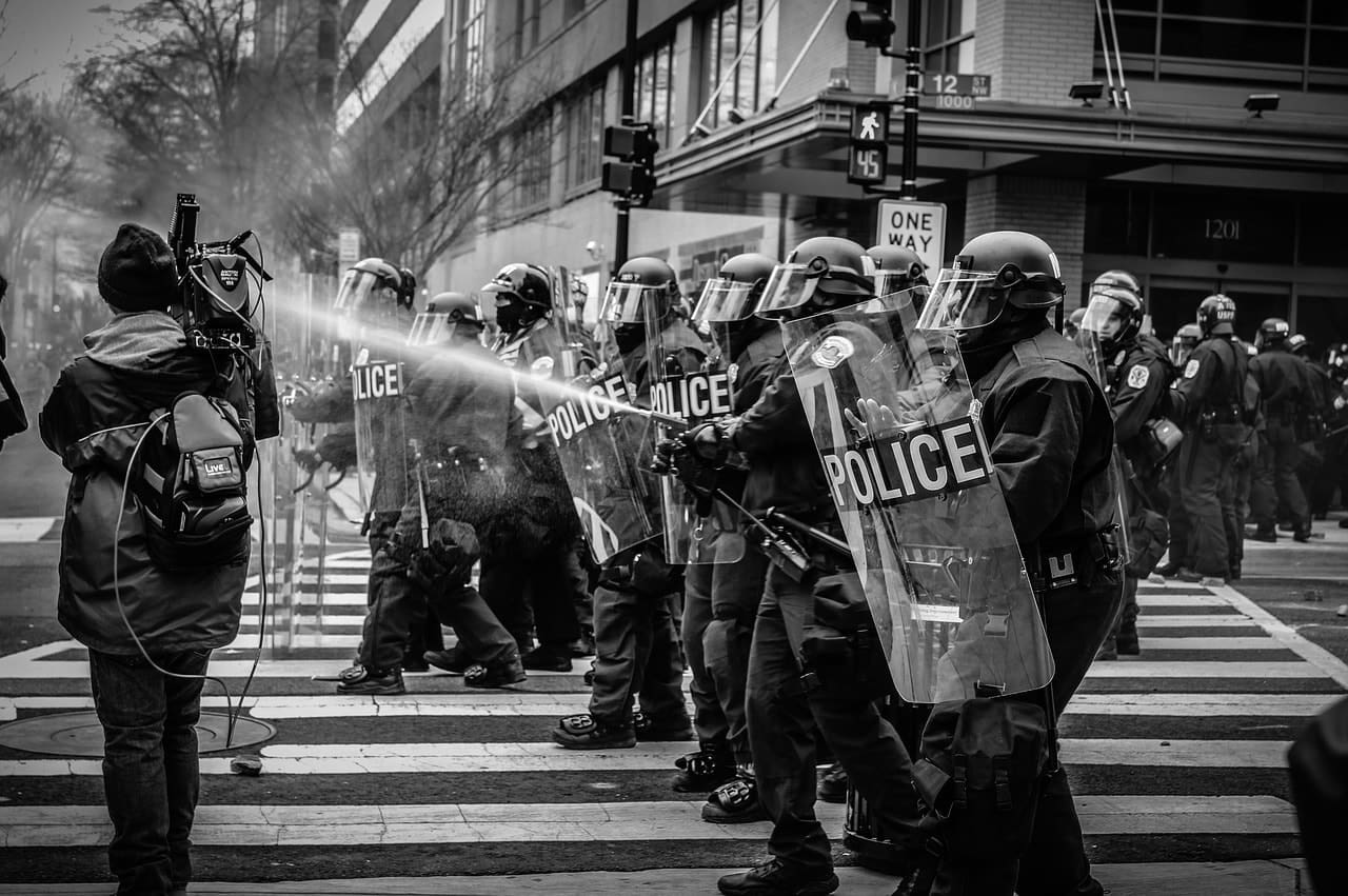 Police officers use water spray to disperse protesters during a demonstration, highlighting tensions between law enforcement and citizens.