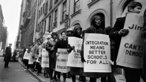 A group of protesters stands on a street, each person holding signs that express their views and demands for change.