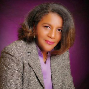 A woman in a suit and purple shirt is posing for a photo.