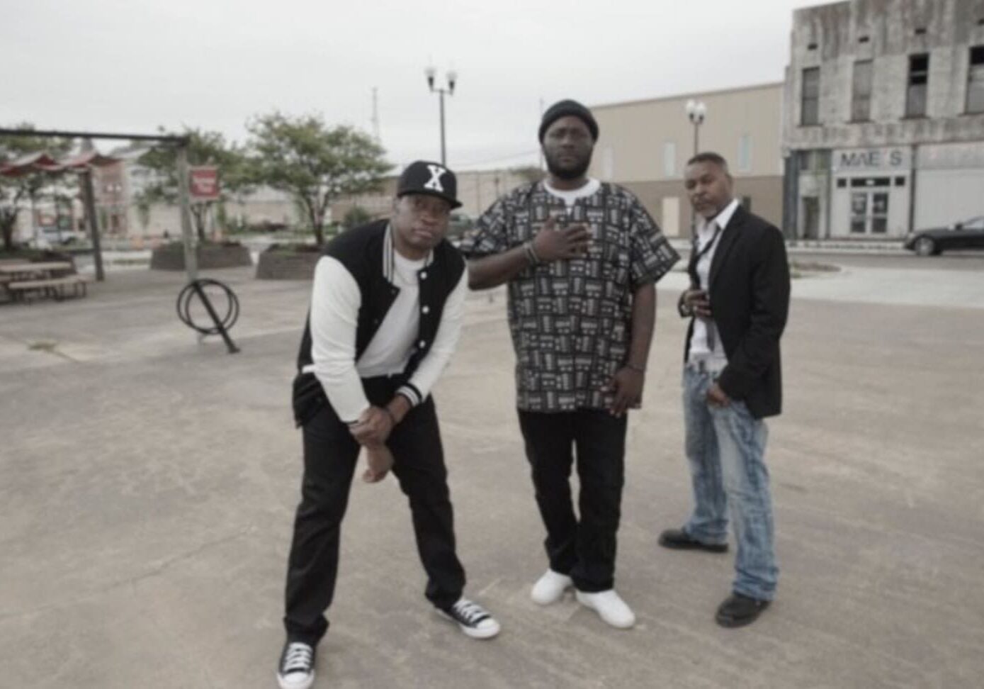 Three men posing together on a city street.