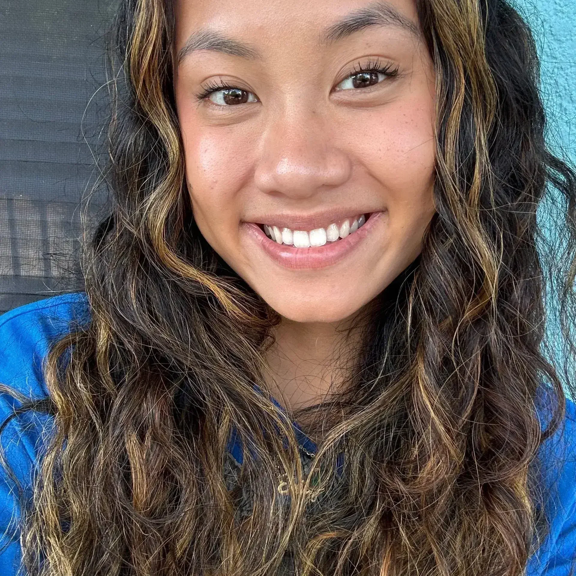 Smiling person with long, wavy hair.